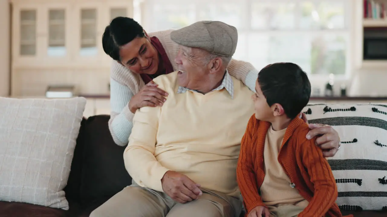 Grandparents hug and boy on sofa at house