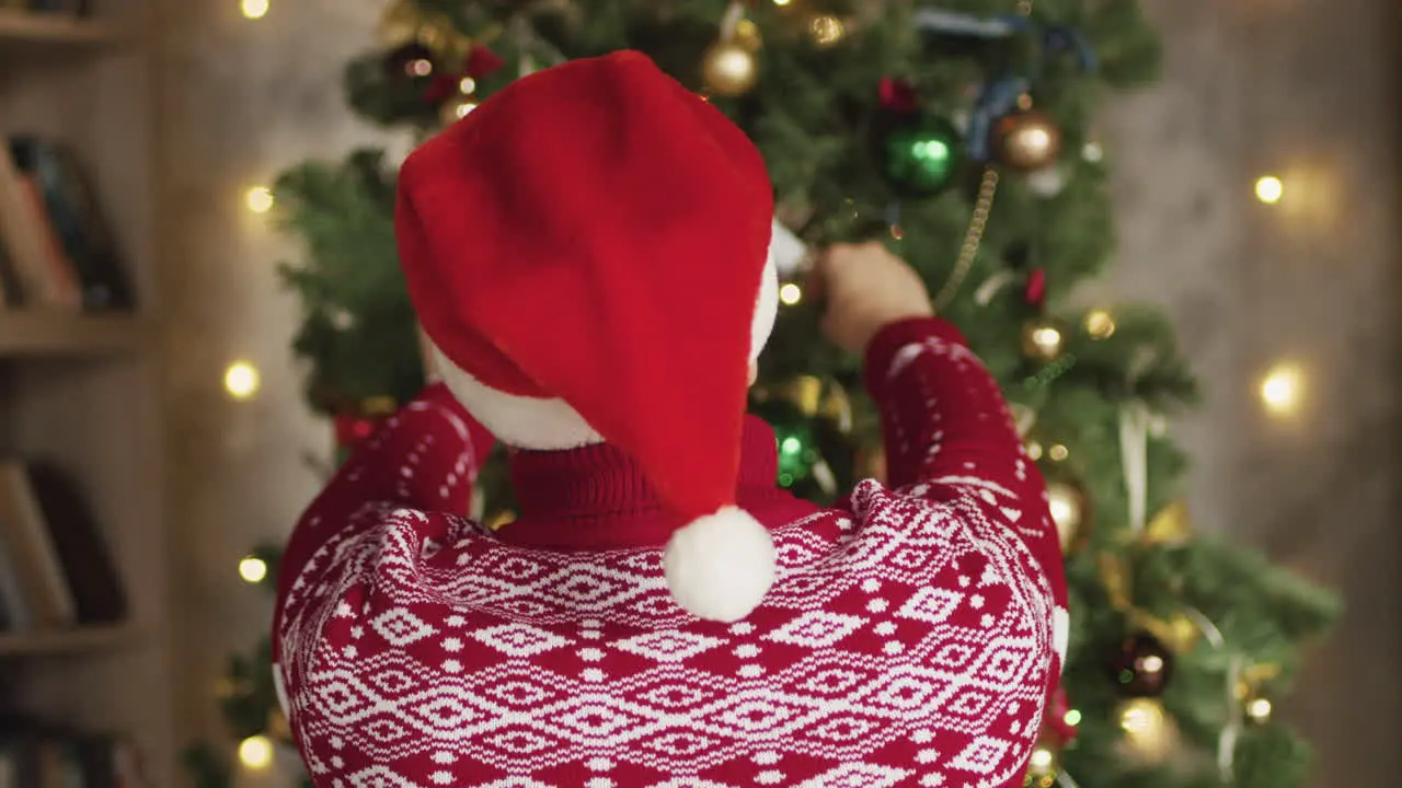 Vista Trasera Del Hombre Poniendo Sombrero De Santa Y Decorando El árbol De Navidad En Casa