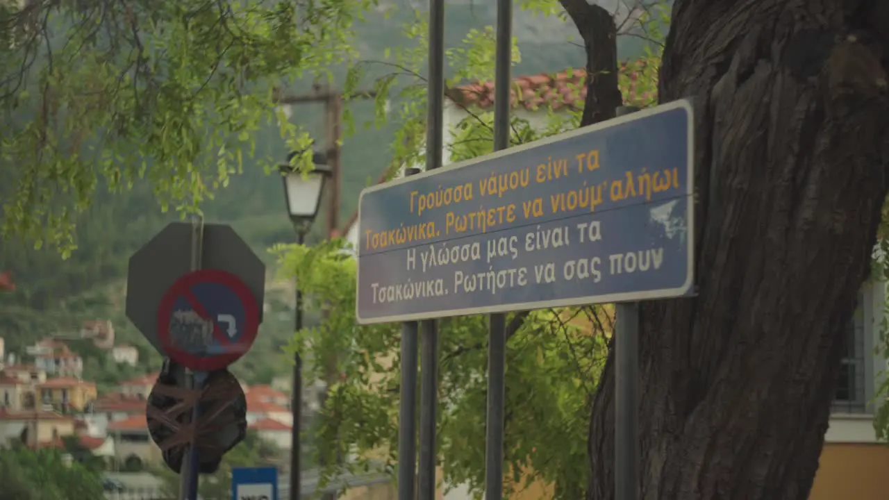 Sign introducing the classic town of Leonidio Greece at entrance below old tree