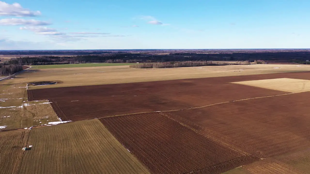 Plowed fields in vast countryside on clear day aerial drone shot