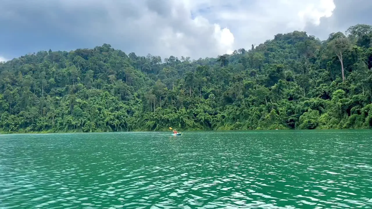 A person canoeing on Khao Sok Lake with the jungle visible in the background