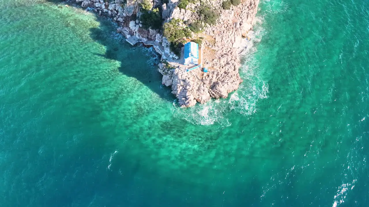 Drone footage over a small Greek Orthodox church on the rock next to the sea