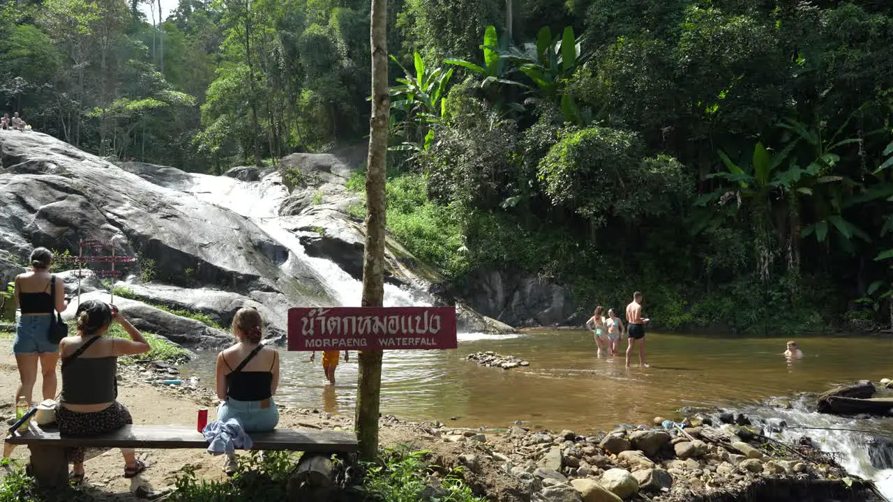 Tourists enjoying Mo Paeng Waterfall in Pai Thailand with lush forest surroundings and clear water