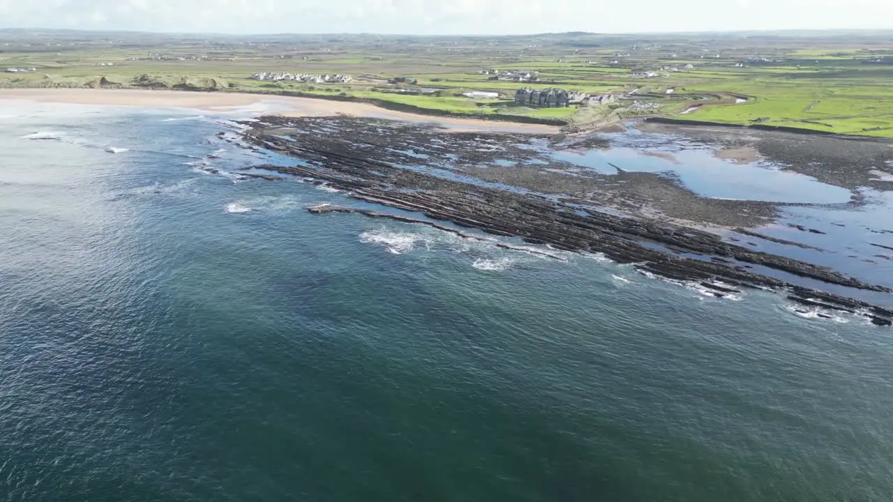 Dughmore Bay with layered rock formations and waves crashing aerial view