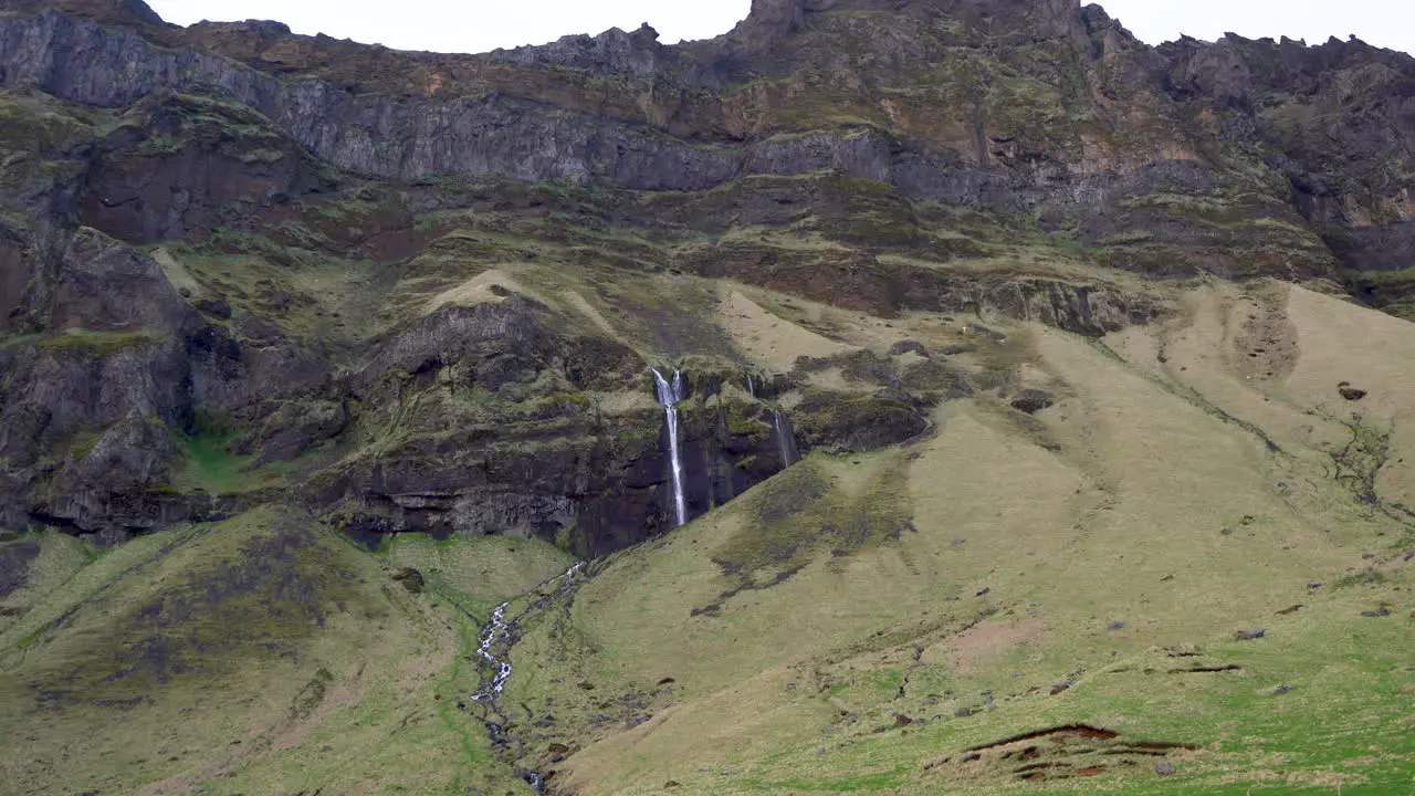 Green mountainside with a cascading waterfall in Iceland showcasing nature's tranquility