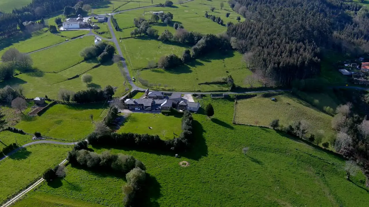 Stone and slate houses of the rural village with grassy fields and mountains in the background with eucalyptus and pine plantations