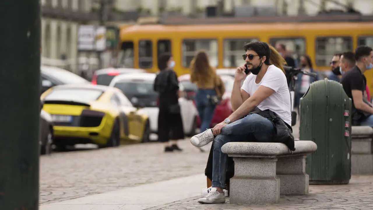 Middle aged man sitting on stone bench talking on the phone