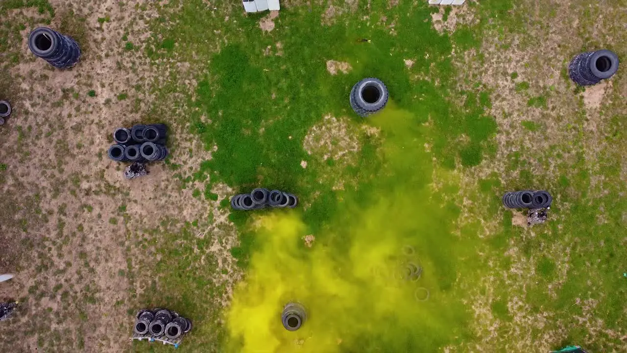 Smoke flare activated on a paintball battle field with players playing a match drone shot