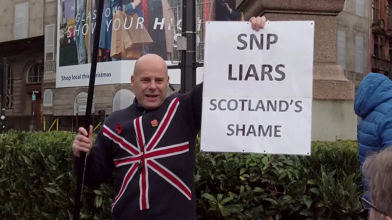 A slow motion and close-up of a British Unionist holding up a sign 'SNP LIARS SCOTLAND'S SHAME'