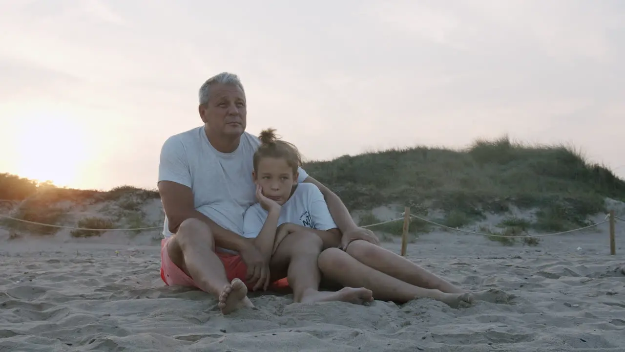 Grandpa and grandson on the beach at sunset