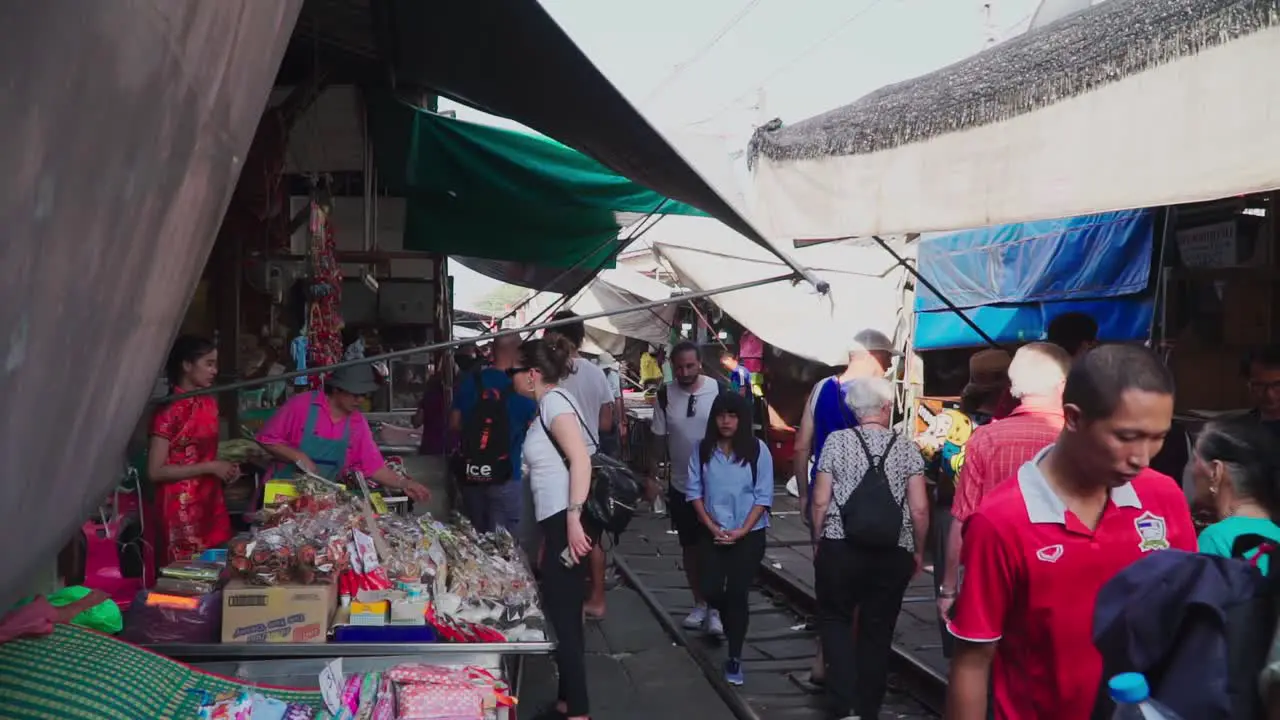 Establishing Shot Tourists walking and checking different shops in the Maeklong Trail Road Market in Thailand