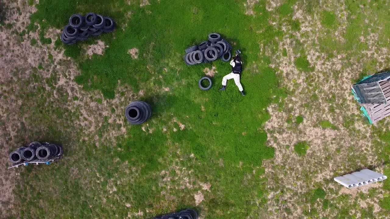 Paintball player doing a stunt throwing himself on the field while playing a paint ball game drone shot