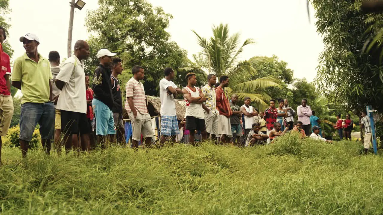 A group of talking people on the street during a "kabar" meeting in a village in the nature under the palm trees