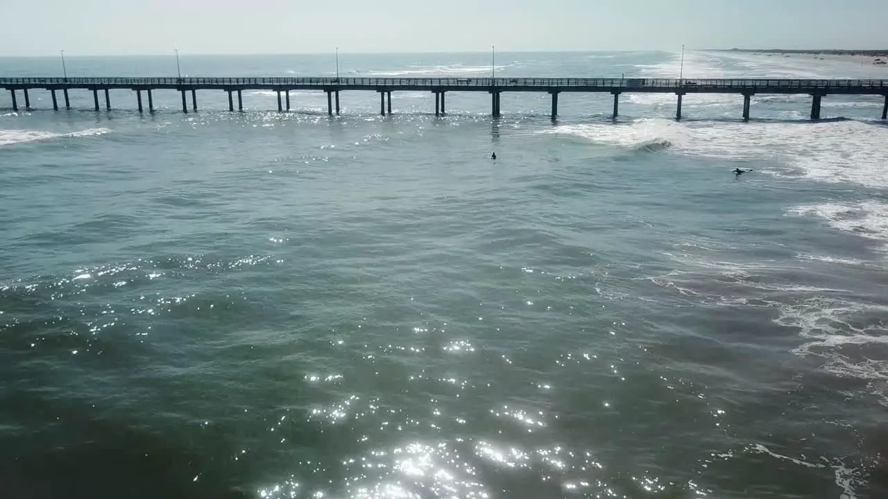 Aerial drone view of several people on paddle boards near a large pier in calm waters of the Gulf of Mexico off the Texas shore North Padre Island Texas