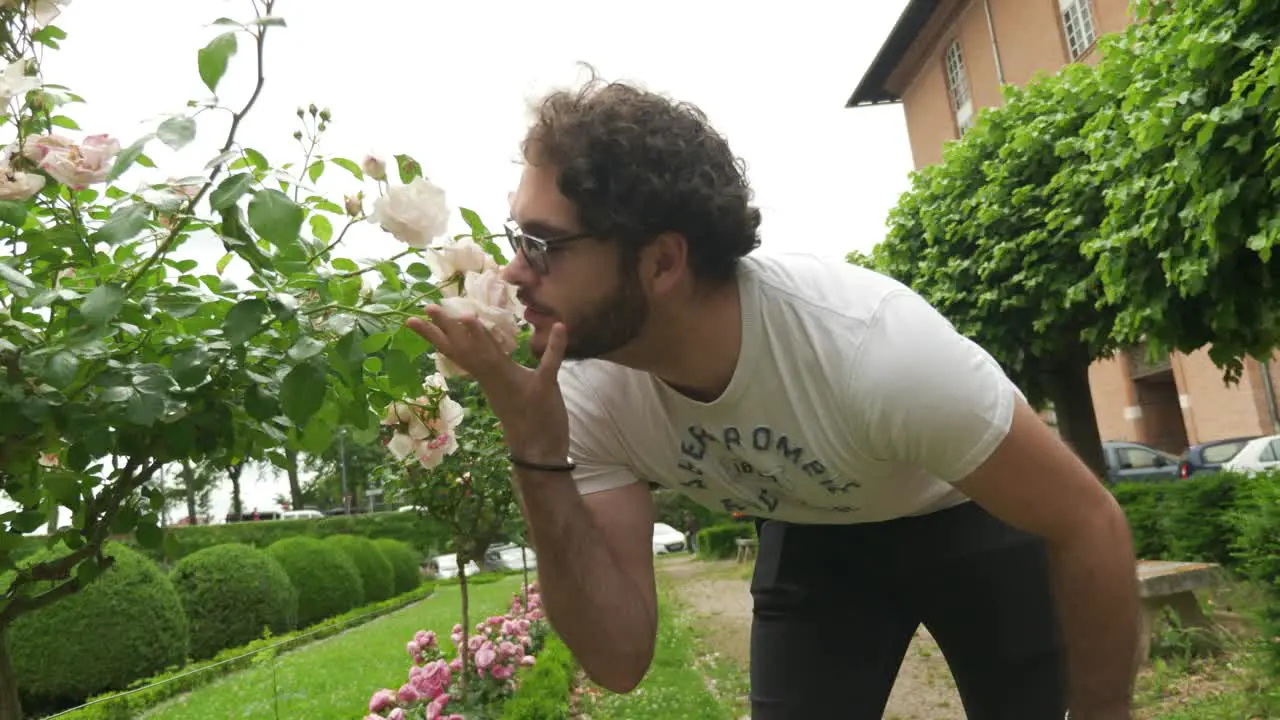 Panning shot of Guy with Glasses smelling Roses