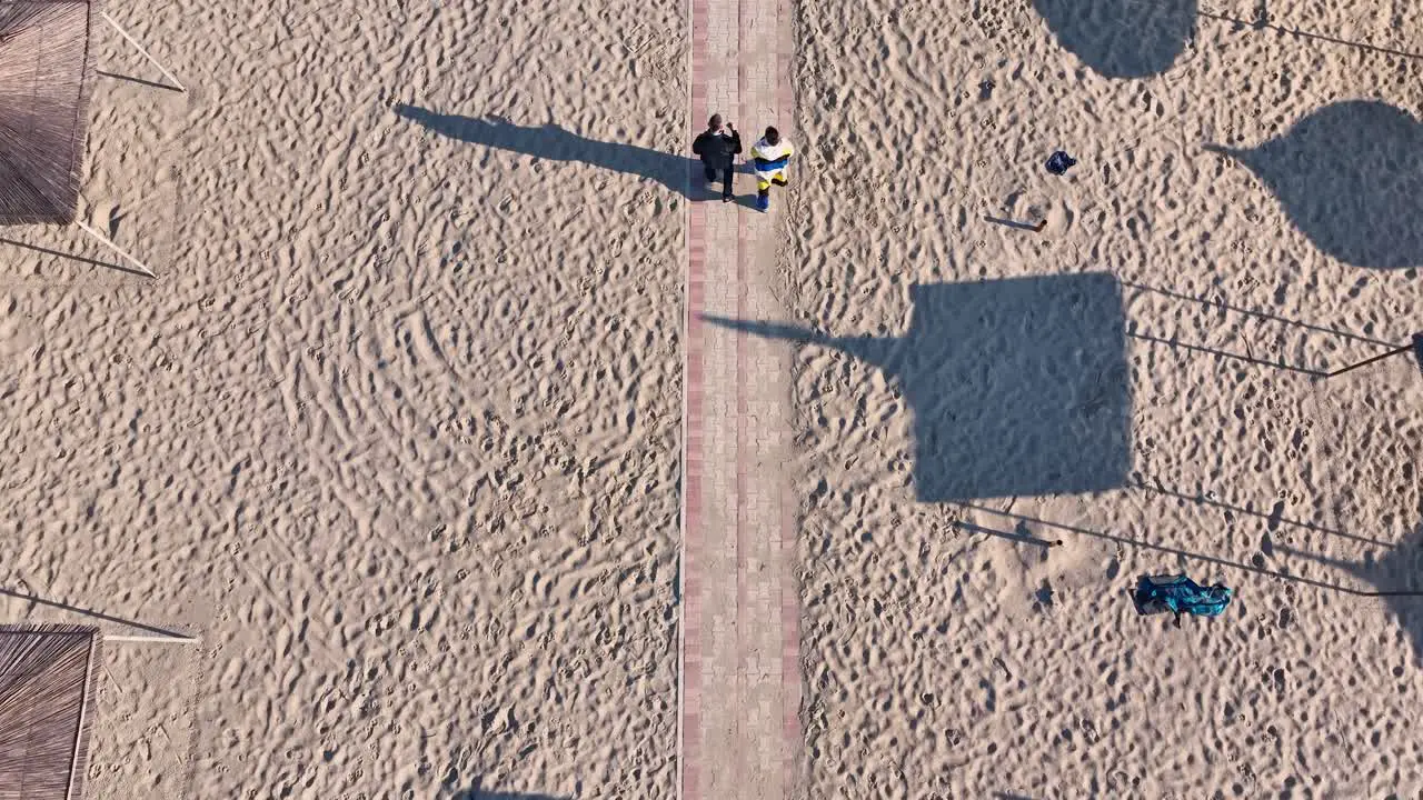 Couple walking on the walkway of a sandy beach in autumn on a sunny day