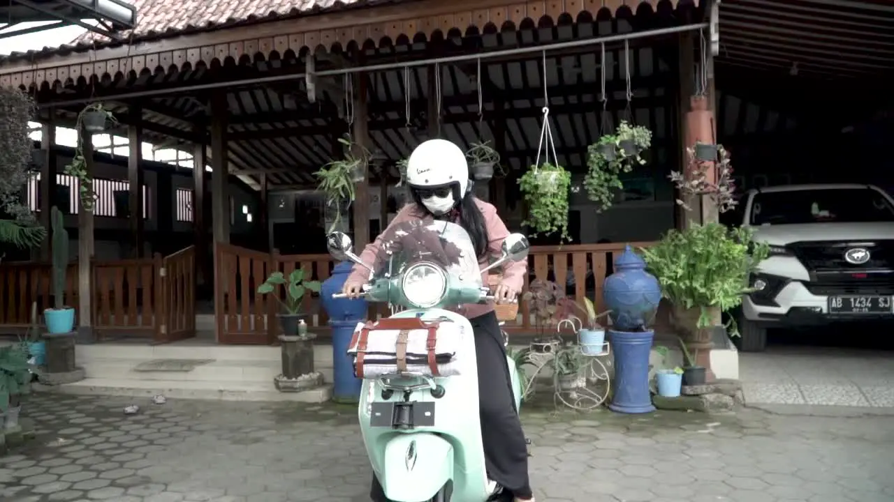 Beautiful woman sits on scooter bike and rides away motion view