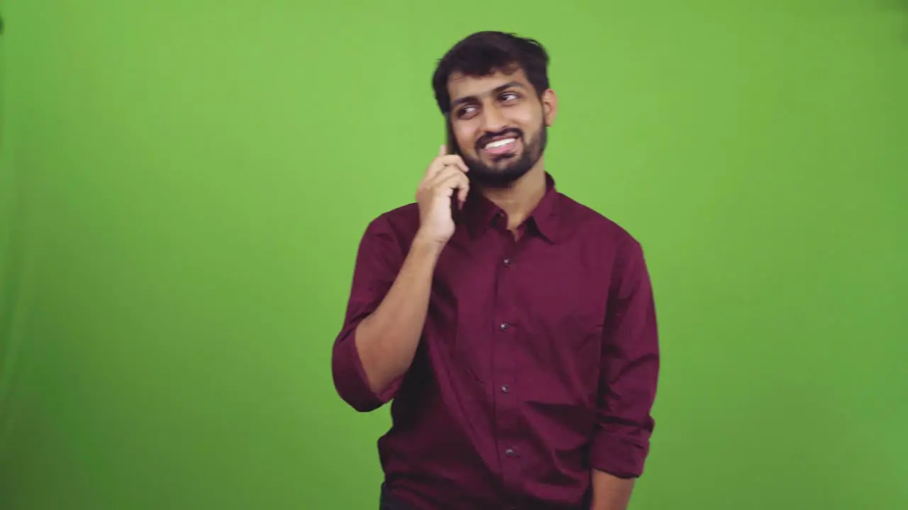 Young Indian male talking on phone with cheerful smile isolated on green screen