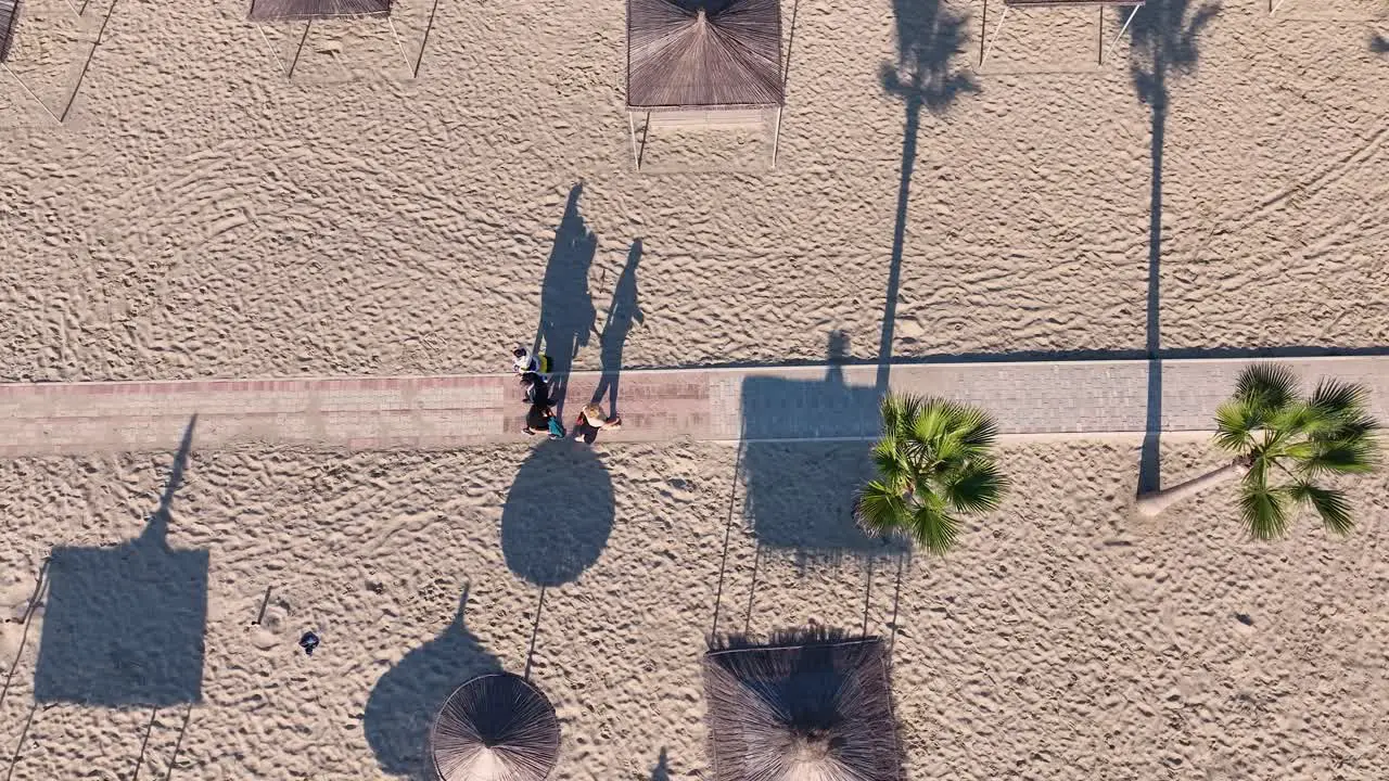 Areal shot of people walking on a sandy beach towards the beach