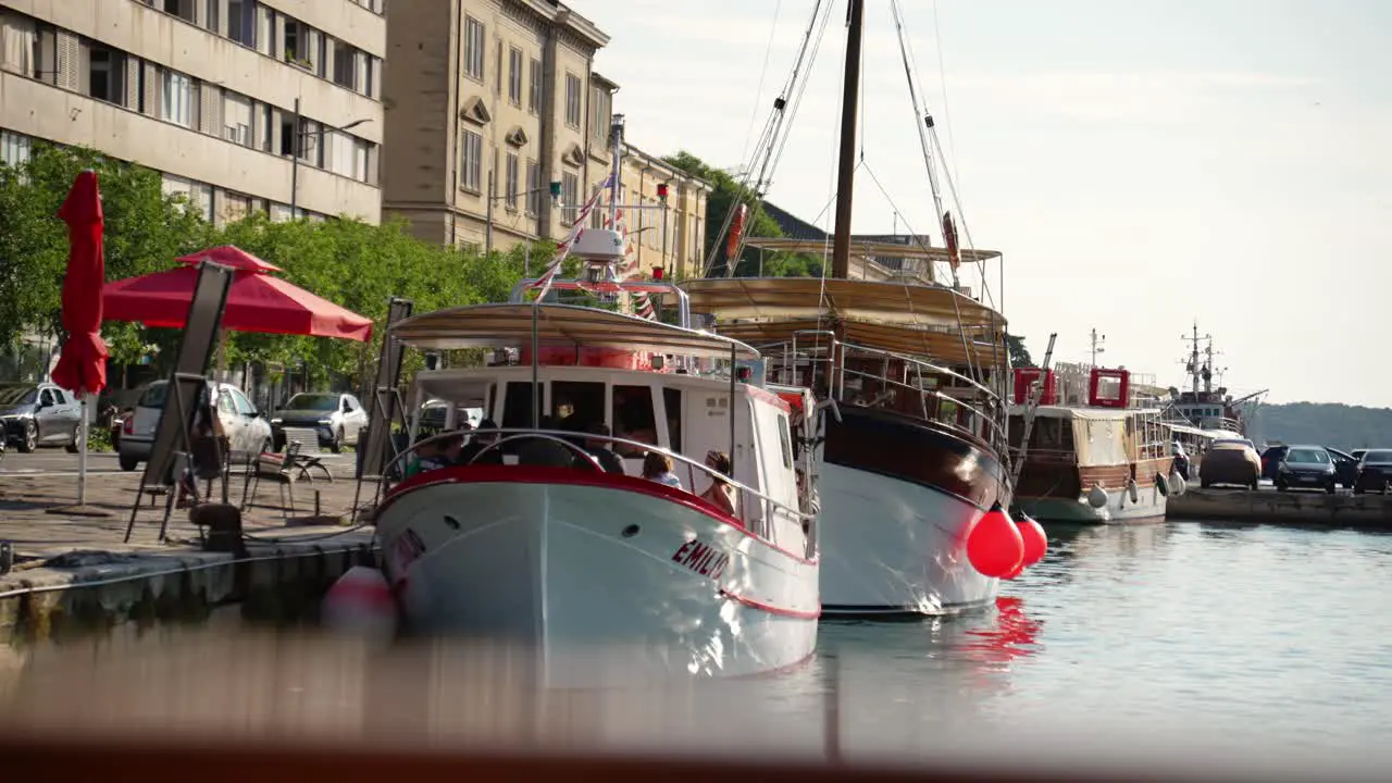 Excursion boat crew and passengers docked at Pula Marina as vehicles go past