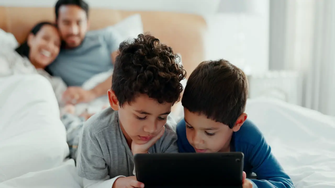 Brothers children and tablet with parents on bed