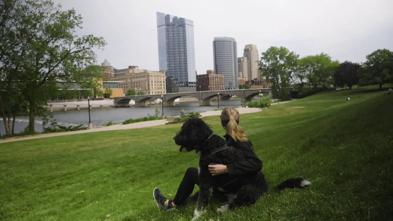 Handheld shot of a young woman sitting in a city park with her dog