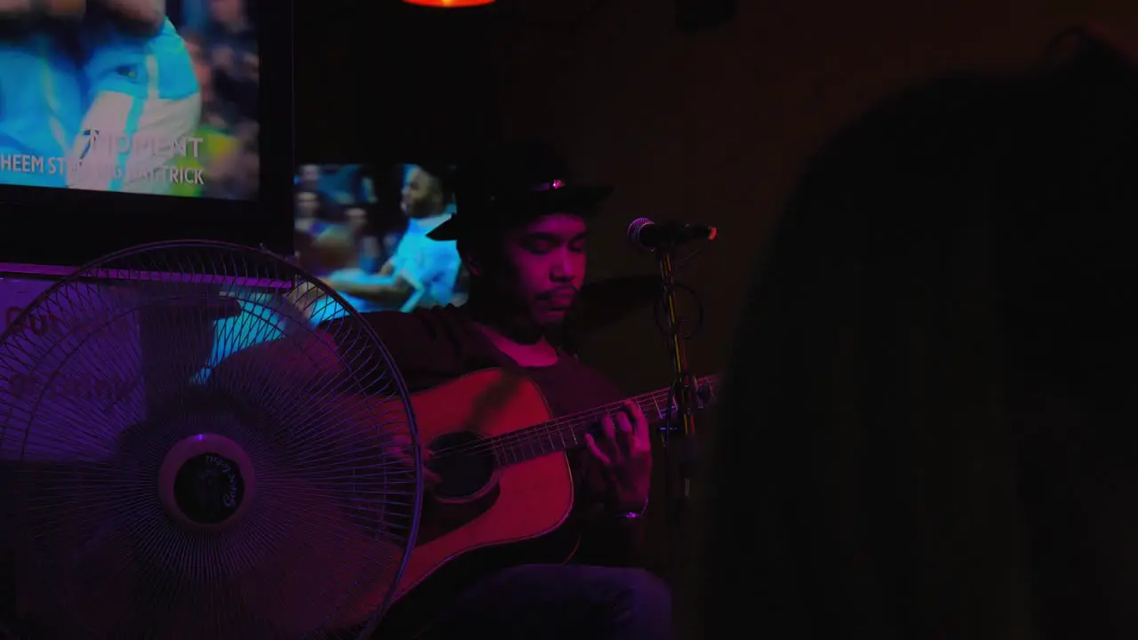 Thai man in a hat playing guitar at Khaosan Road in Bangkok Thailand