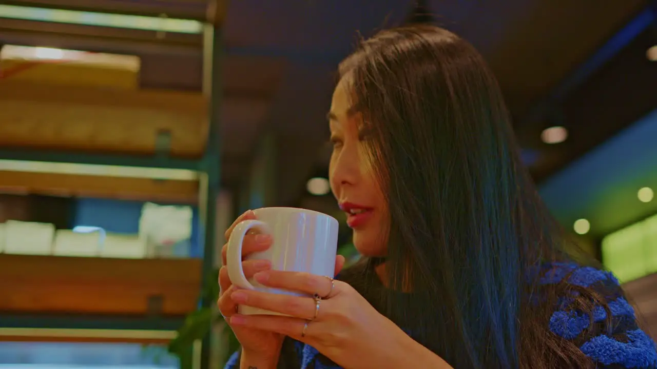 beautiful Asian oriental female girl woman model in cafe restraurant with a cup of beverage drinking talks chats smiles fun and dialogue conversation