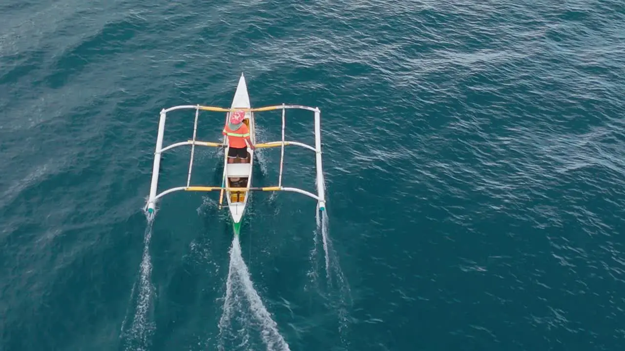 Aerial of a fishermen's outrigger being towed by a large fish by handline