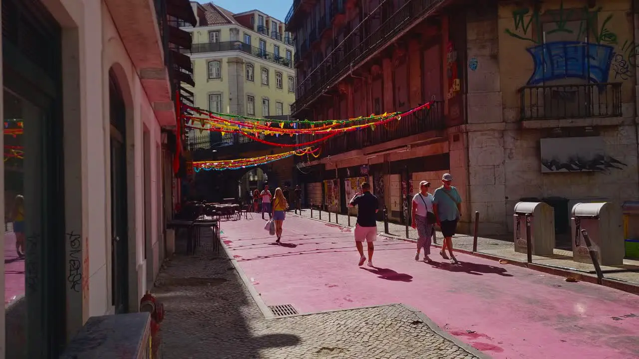 Narrow streets of Lisbon illuminated by bright sunshine as people sightsee