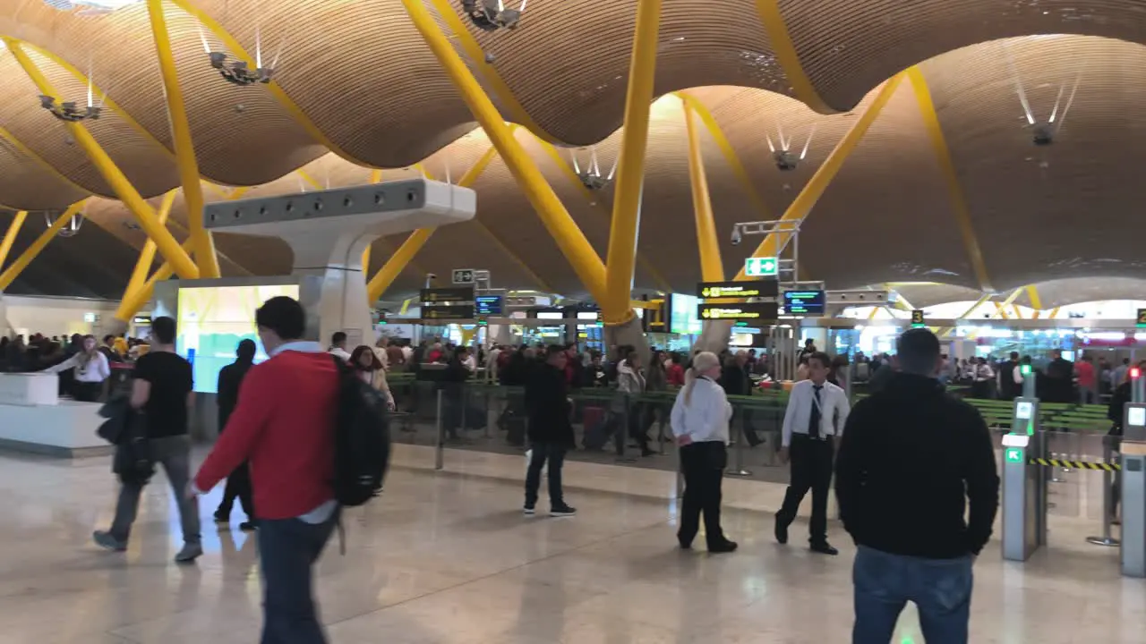 Slow pan to the right of people walking on a terminal of Madrid airport