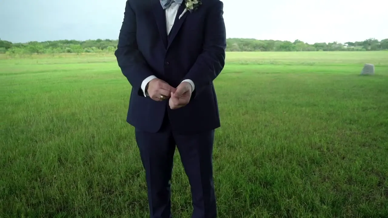 A groom fixes his cuffs