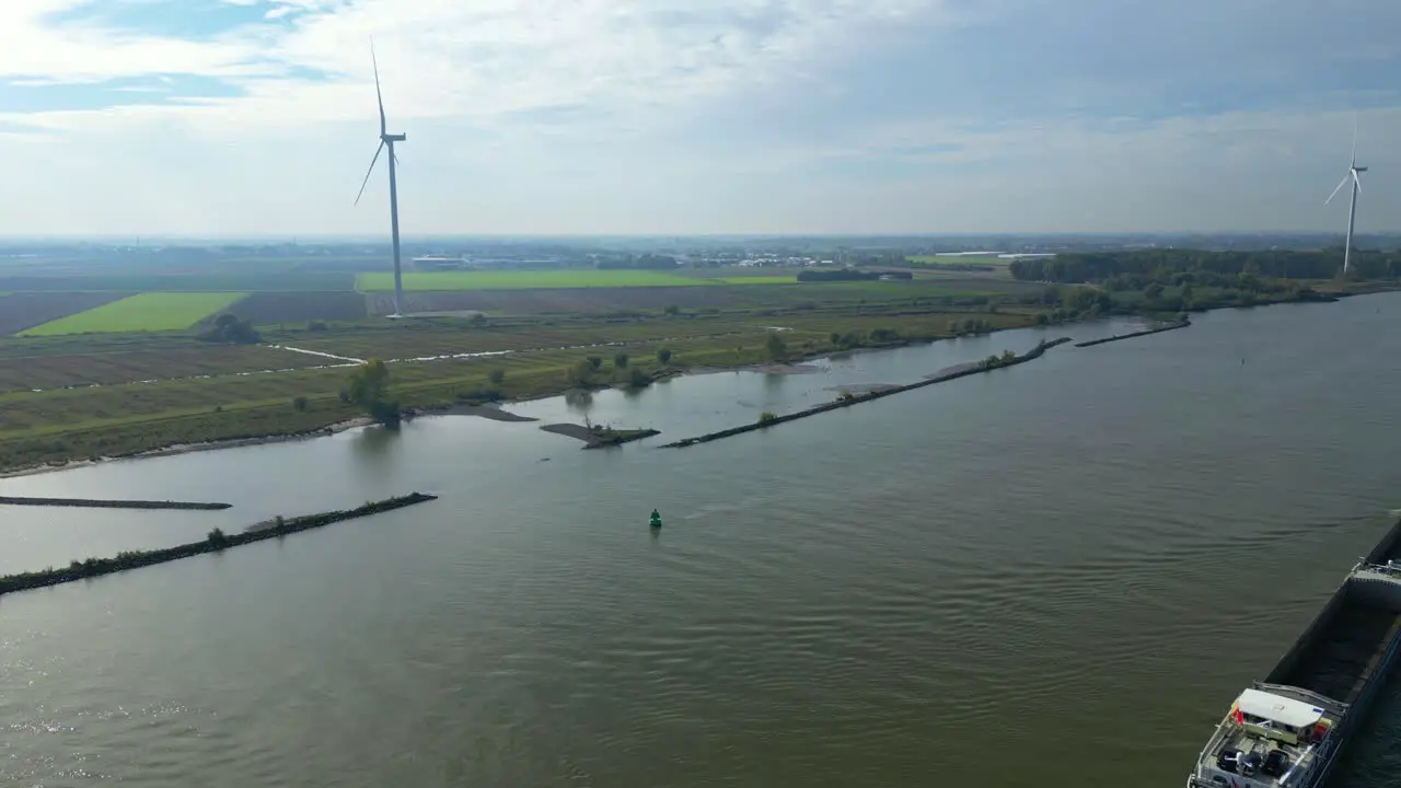 Aerial View Of Giant Wind Turbine With Dolly Right Over Oude Maas With Barge Passing By