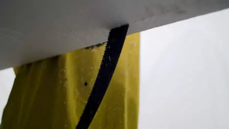 Handheld Close Up Shot of a Saw Cutting Through a Polystyrene Surfboard