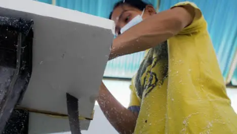 Handheld Low Angle Shot of a Surfboard Shaper Cutting a Polystyrene Board