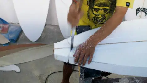 Handheld High Angle Shot of a Surfboard Shaper Cutting Polystyrene Board