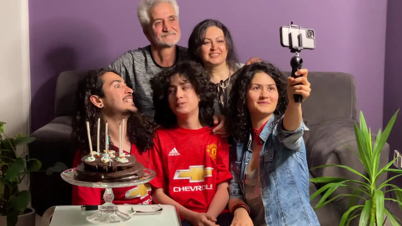 A Persian Iranian family party birthday ceremony curly hair people at home in Tehran Iran Senior man closing woman eyes for surprise Excited mature woman looking at cake with burning candles