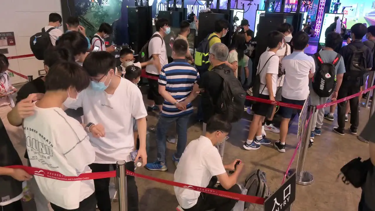 Chinese gamers and young visitors queue in line to play virtual reality shooting videogames during the Hong Kong Computer and Communications Festival