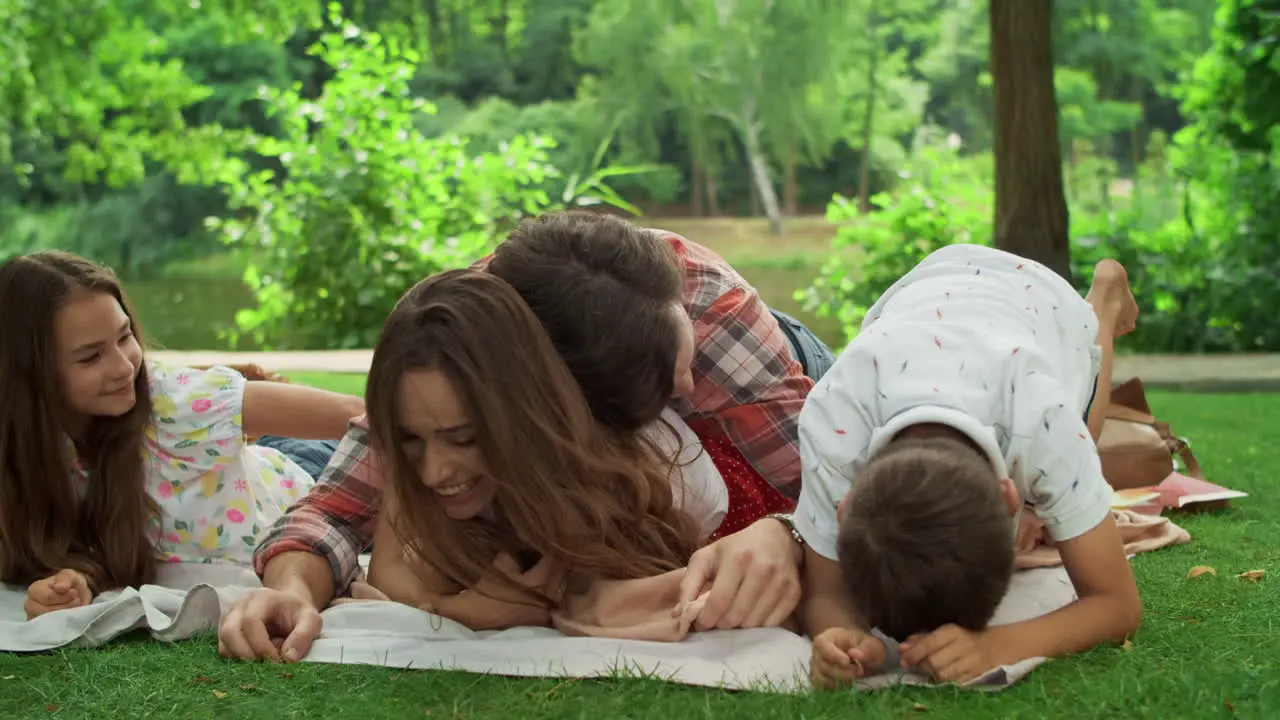 Family having fun in park Children with parents lying on blanket in forest