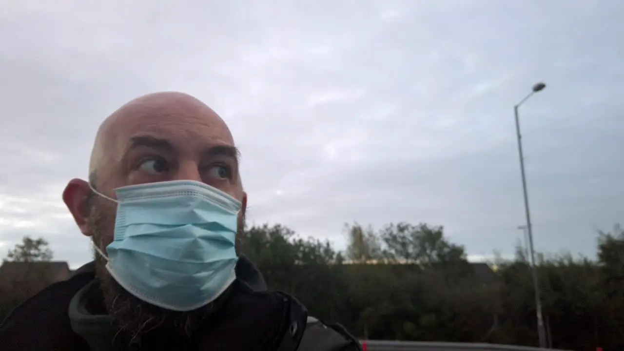 Male in workplace wearing uniform and PPE face mask against corona virus looking around