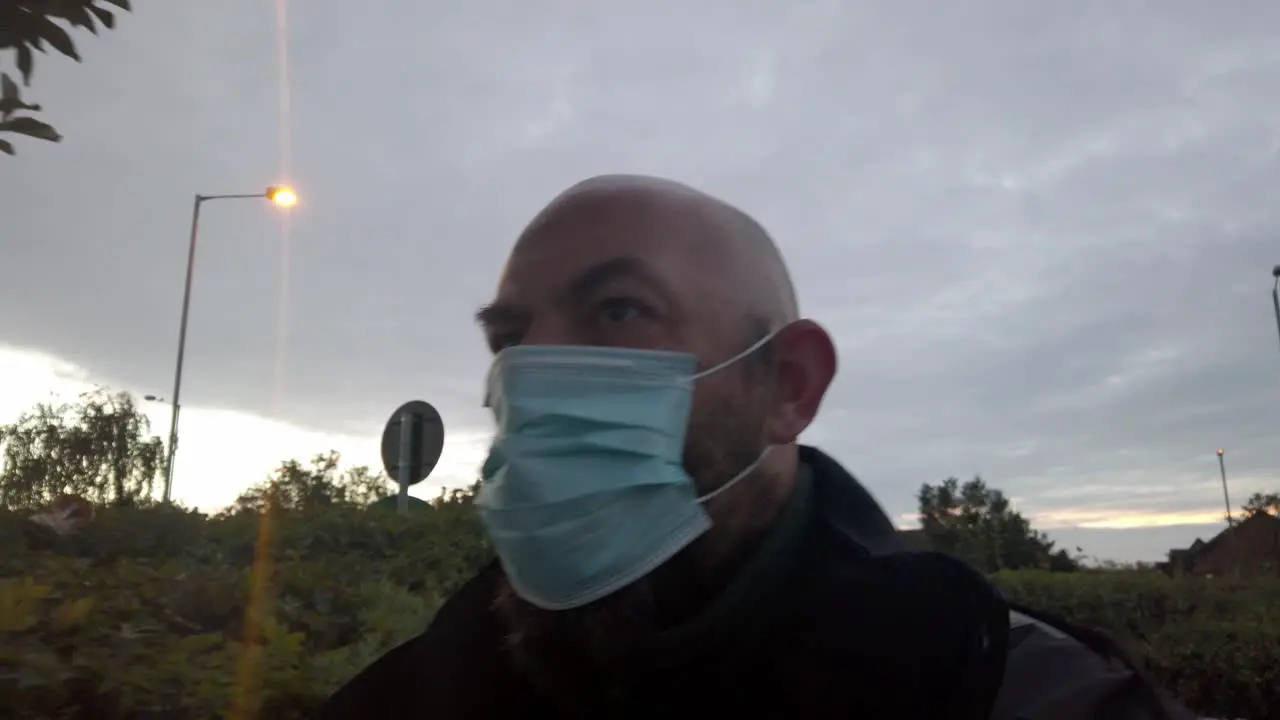 Male in workplace wearing uniform and PPE face mask against corona virus walks under tree