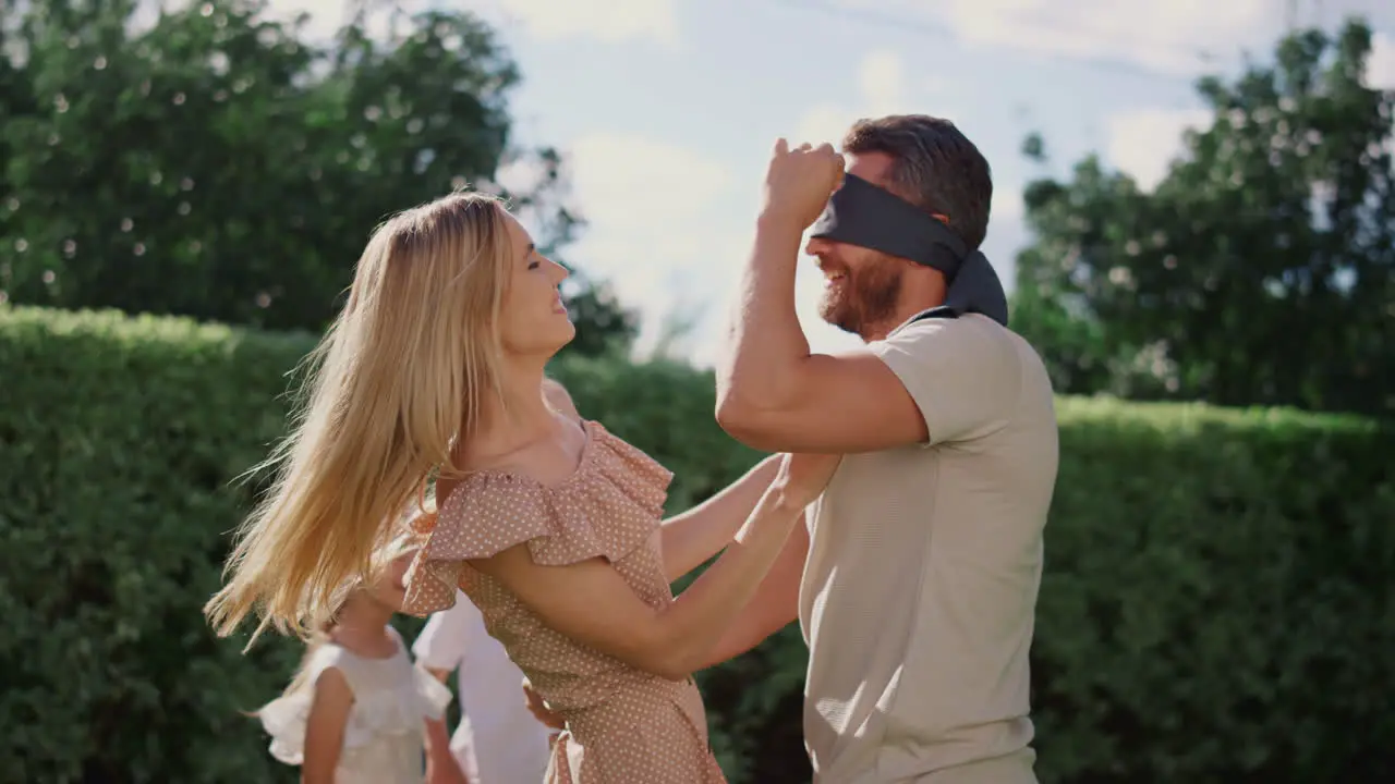 Family playing blind man buff in garden Happy father in blind catching boy