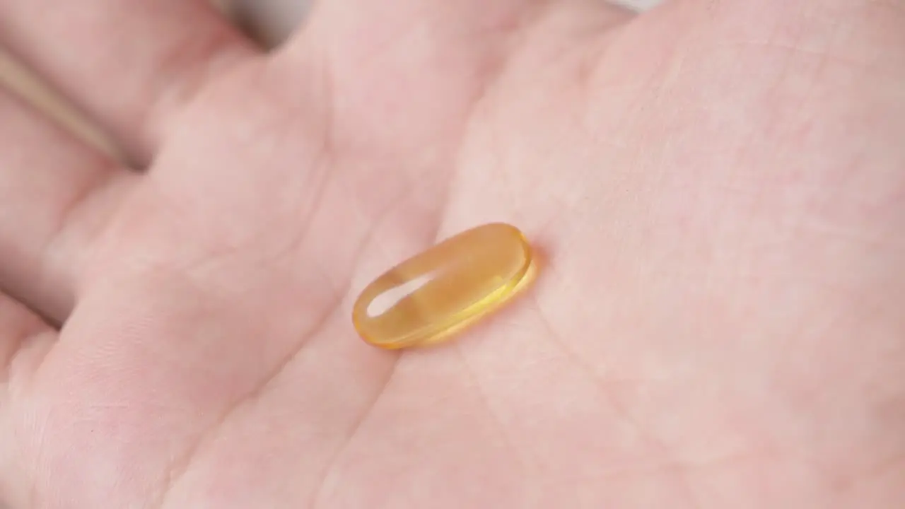 Hand showing an omega-3 fish oil capsule to the camera