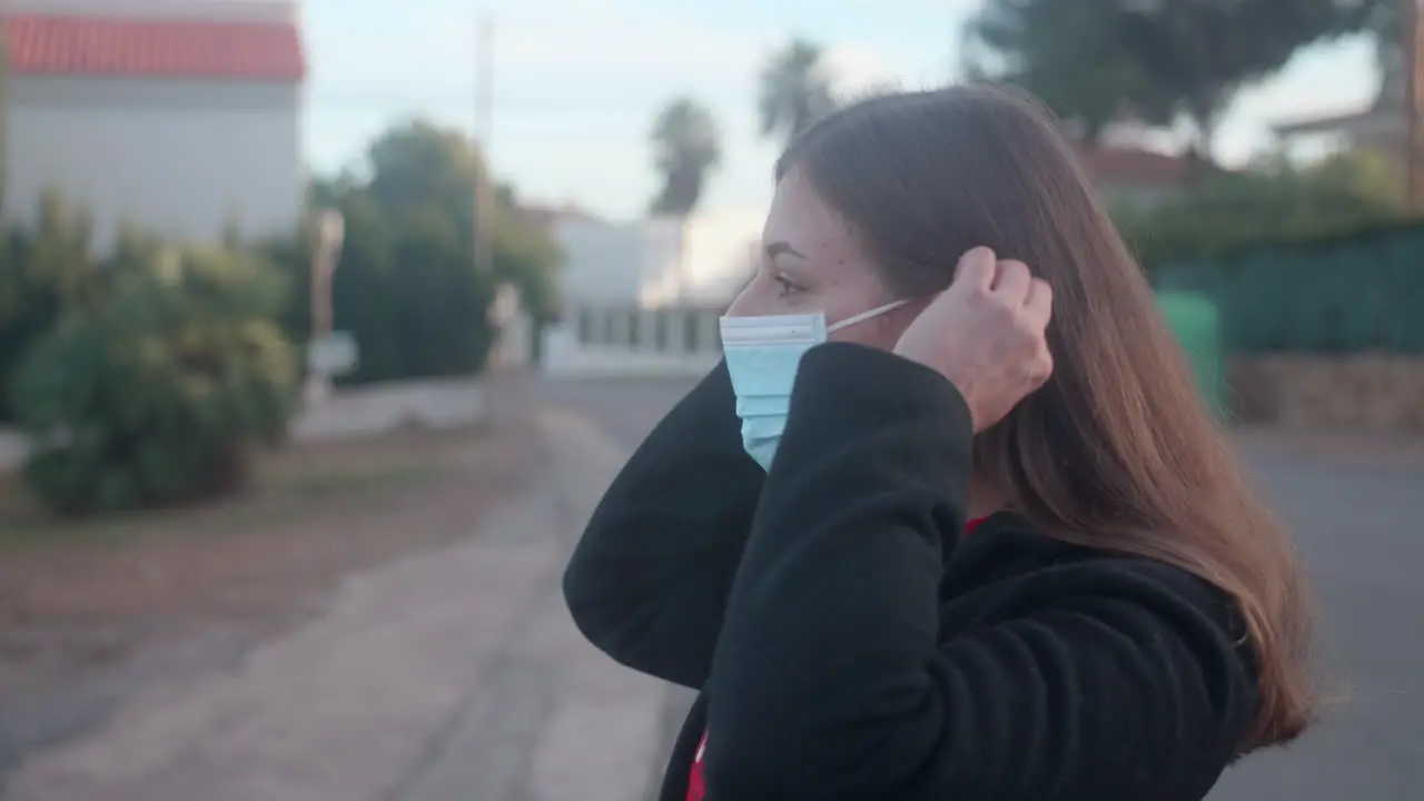 Woman putting on a surgical mask in the street