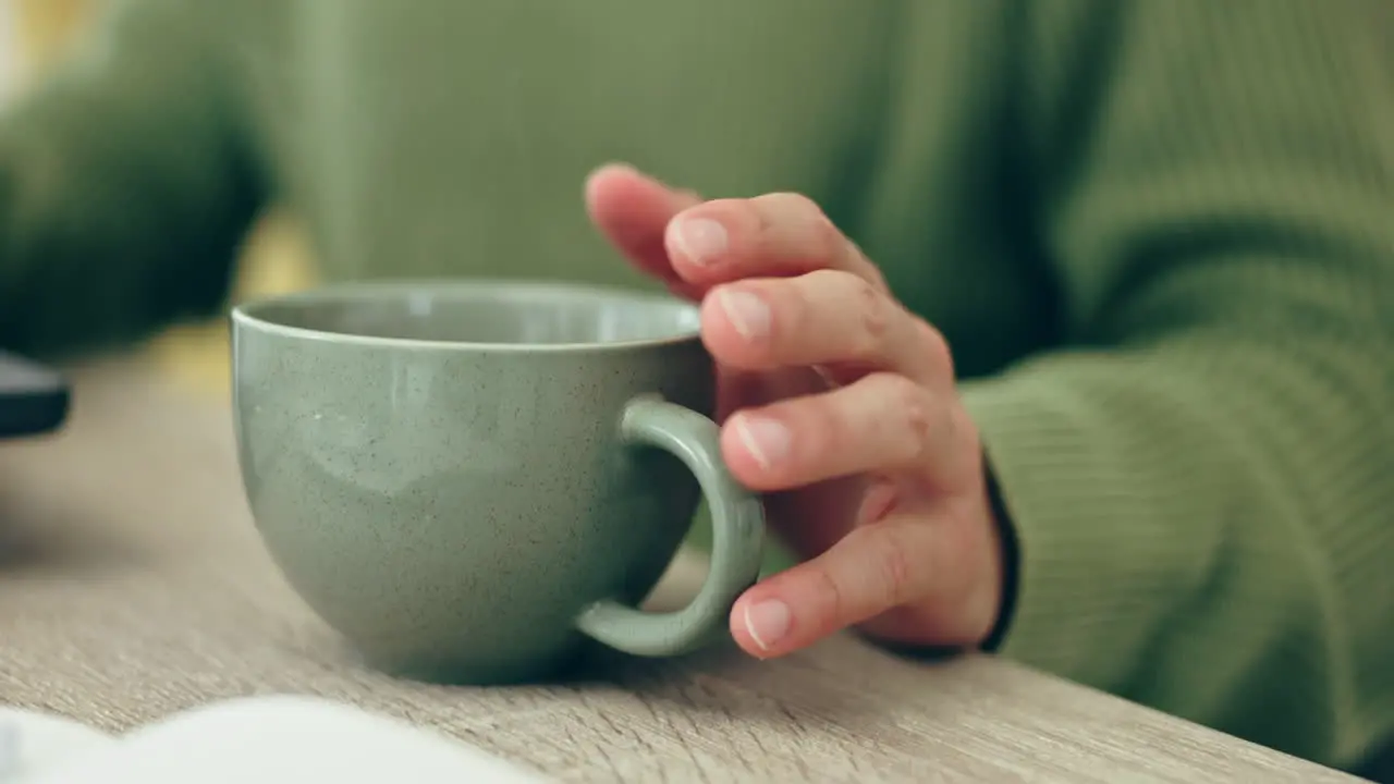 Mug tapping coffee and hand at a table for remote