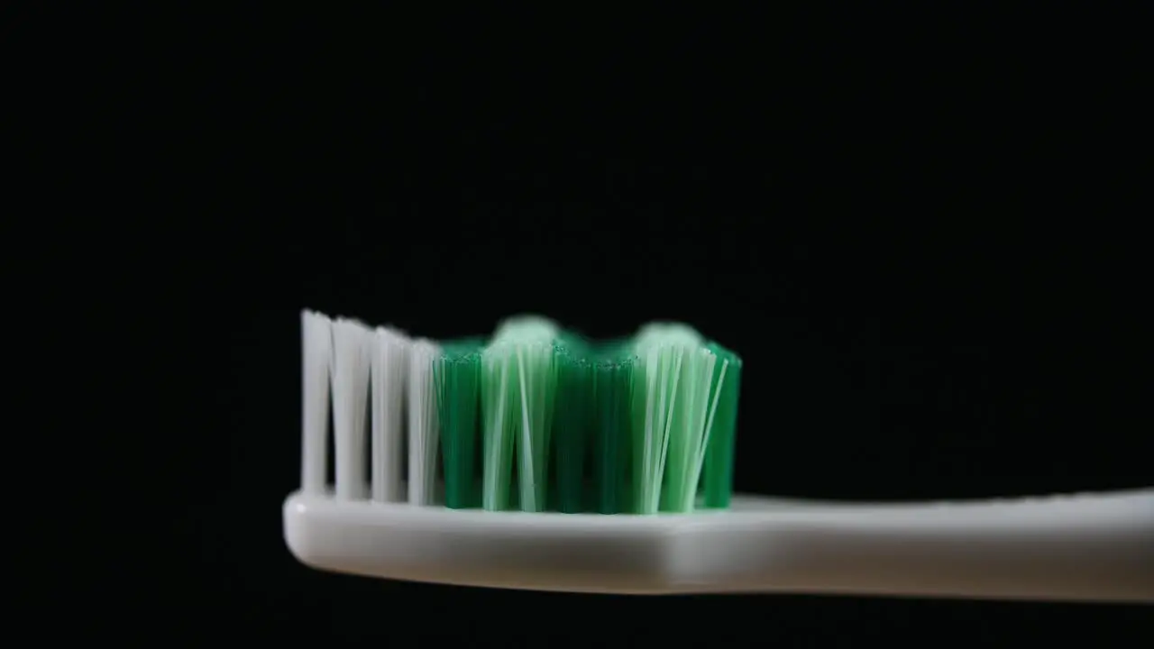 A toothbrush zoomed out with a dark background revealing bristles and the handle