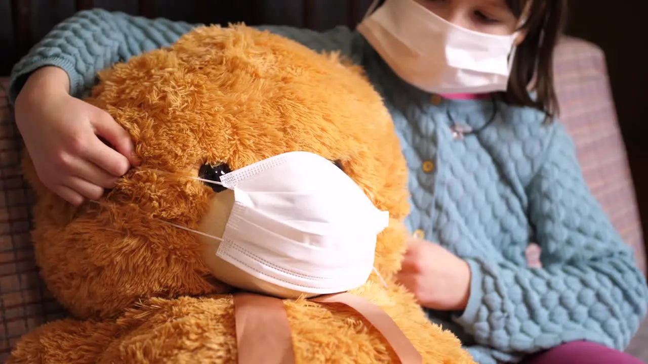 Young girl wears mask puts mask on stuffed animal Covil-19 quarantine