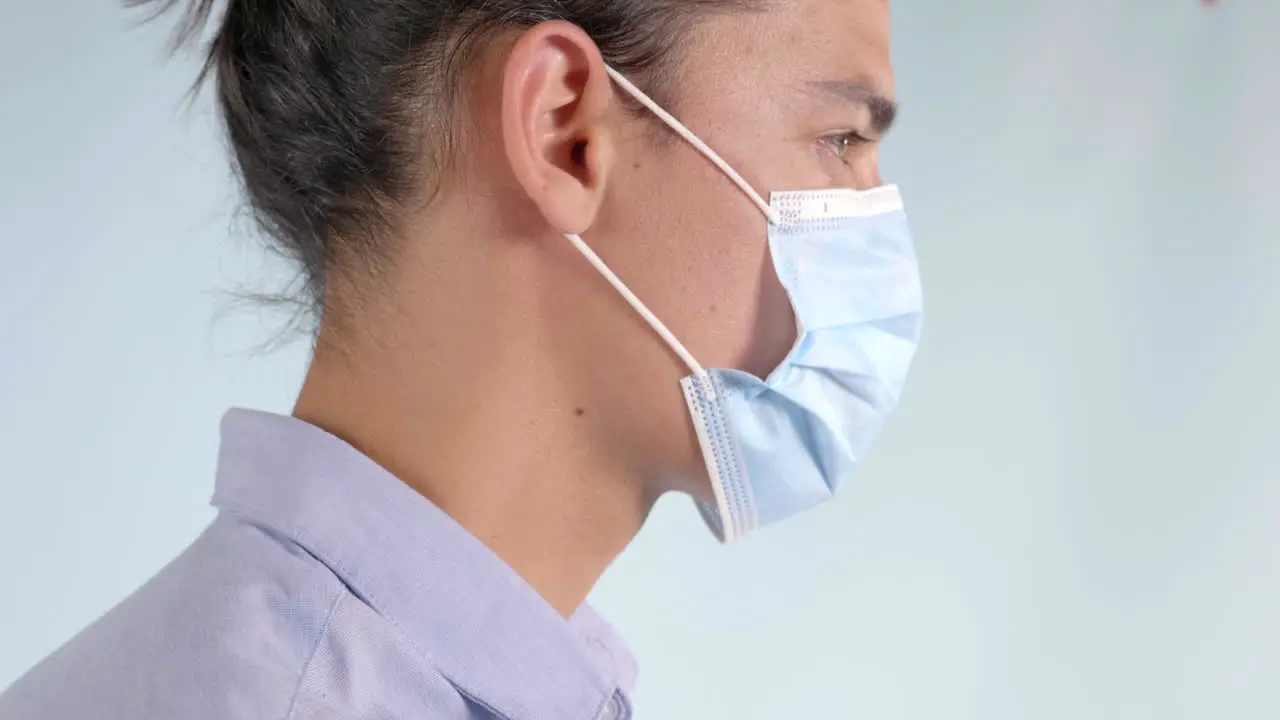 Man facing right puts on blue face mask Extreme Closeup Profile