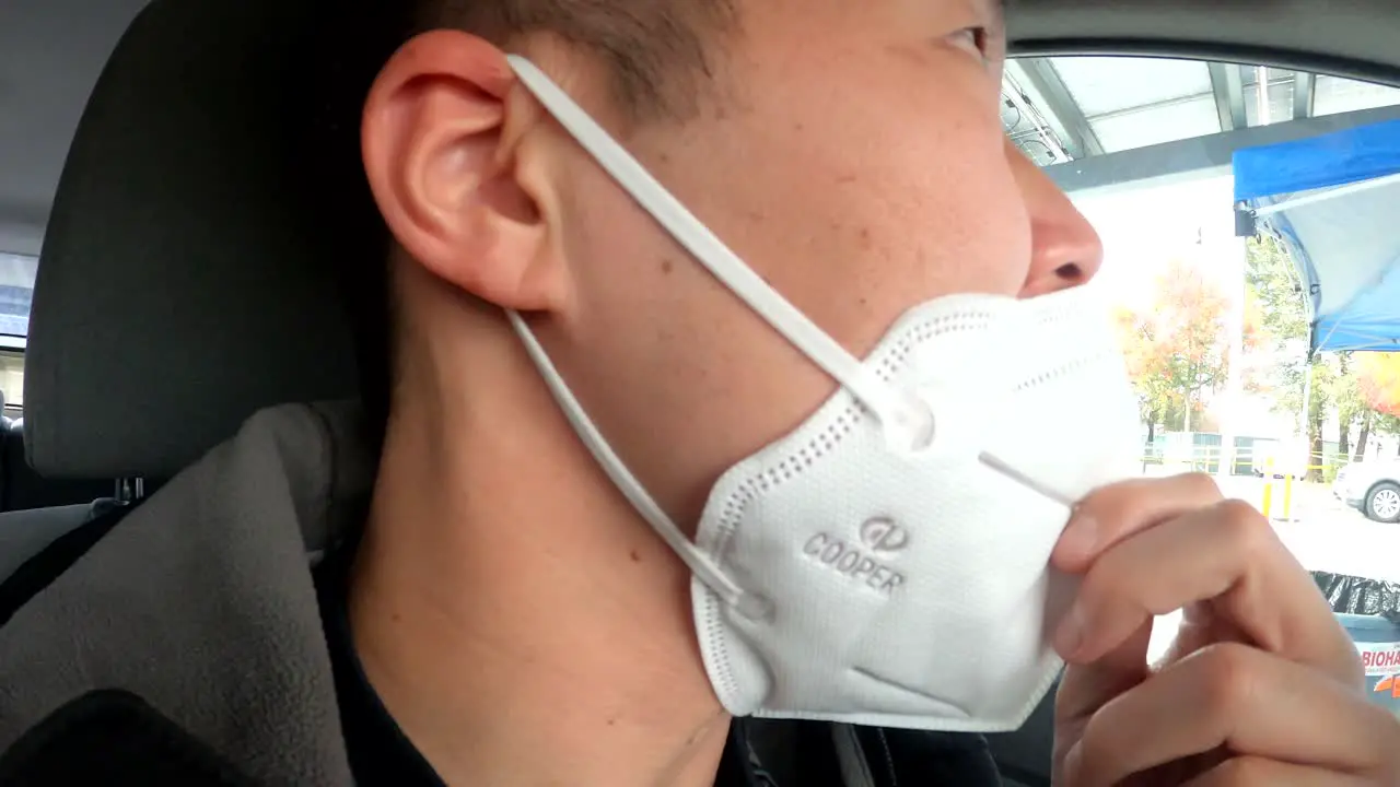 Asian male in early 40s testing for COVID19 with a nasal swab at a drive-thru free testing site in Santa Clara County California 