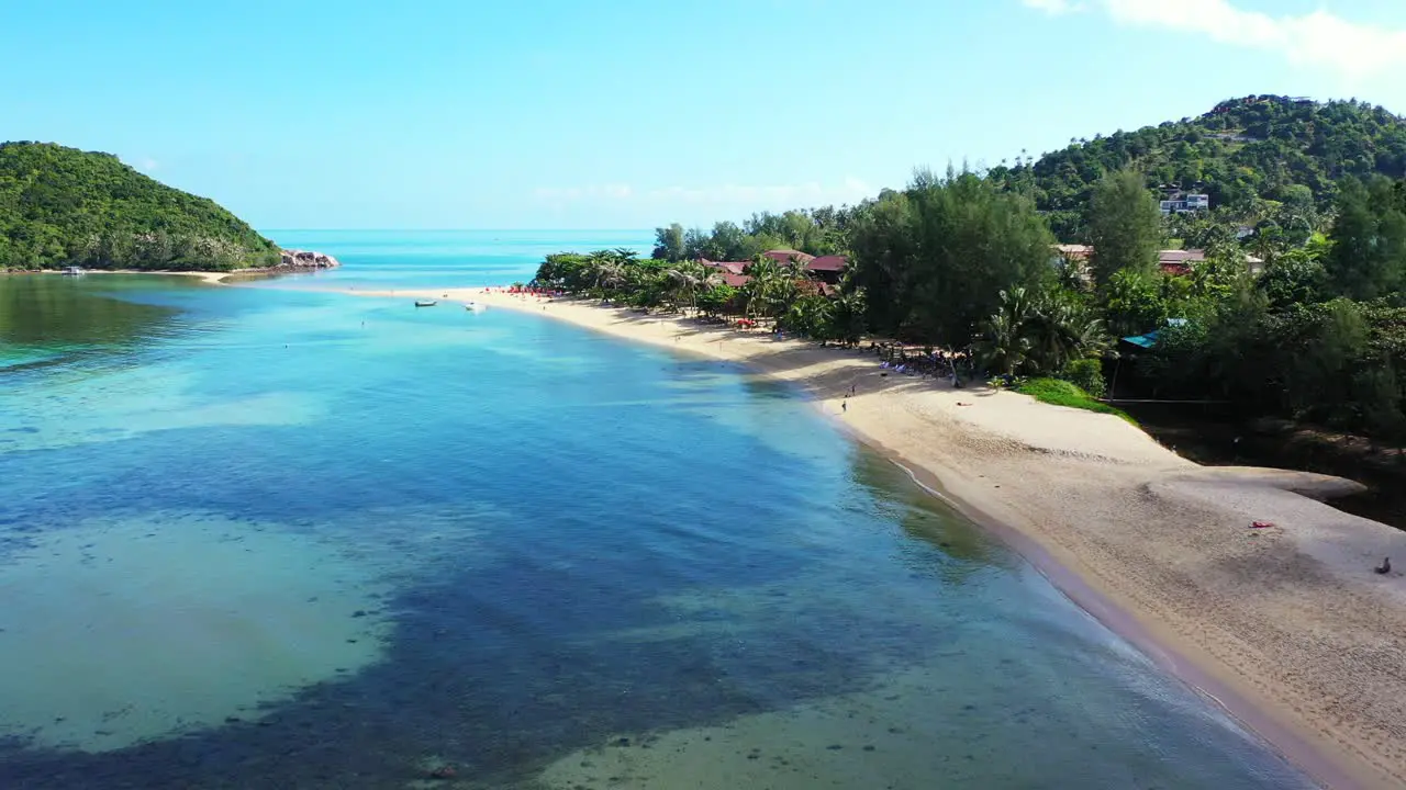 Calm clear water of lagoon with beautiful patterns of corals and algae near sandy beach on tropical island with lush vegetation